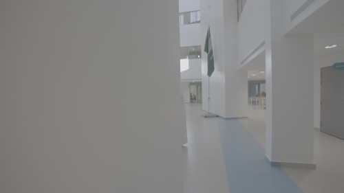 The video showcases a tour inside a modern building in Saudi Arabia, where two men in traditional Saudi attire exchange papers and review documents in a wide, well-lit atrium. The Saudi flag is also visible in the corner, emphasizing the formal setting.