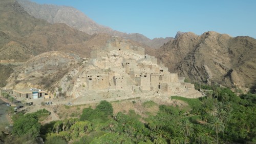 Aerial video of an ancient stone village nestled between mountains, showcasing traditional buildings surrounded by greenery, highlighting the surrounding mountainous terrain.\r\n\r\n-