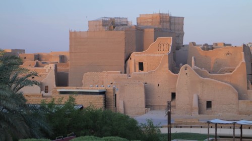 فيديو يعرض مشاهد البناء المعماري التقليدي في منطقة الدرعية الطينية بالمملكة العربية السعودية, تظهر البيوت الطينية القديمة والتفاصيل المعمارية التي تمثل التراث العربي الأصيل وسط أشجار النخيل.