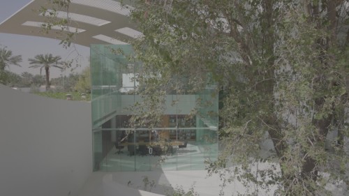 Scenes from a video show a modern library with glass walls and a stylish meeting table. Individuals in traditional attire are seen inside, browsing books and interacting in a calm and well-lit environment.